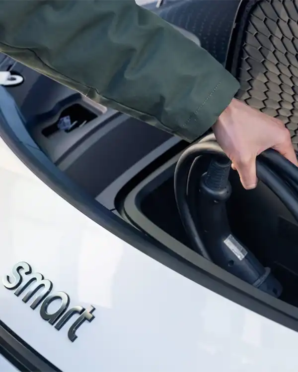 Man putting away the electric charger for his white smart #1 electric car