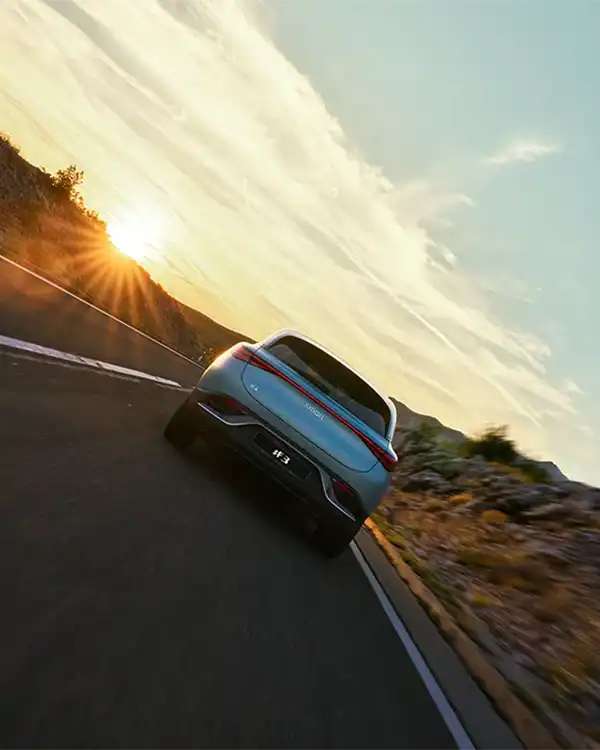 Rear view of a blue smart #3 electric car driving at sunset, with an angled camera position