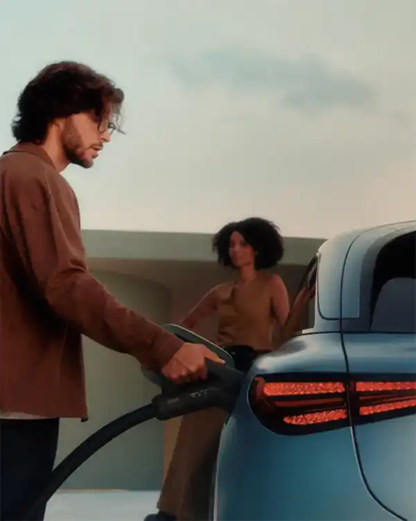 Man charging his blue smart #3 electric car with a woman standing near by