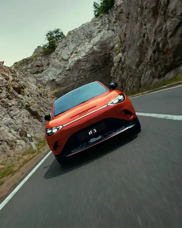Front view of a red smart #3 BRABUS electric car driving on a mountain road, with an angled camera view
