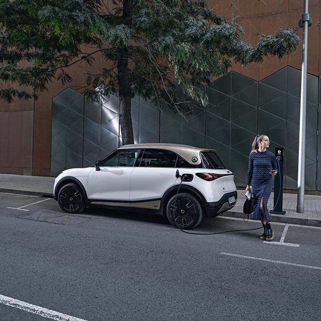 Woman charging her white smart #1 electric car at a public charger