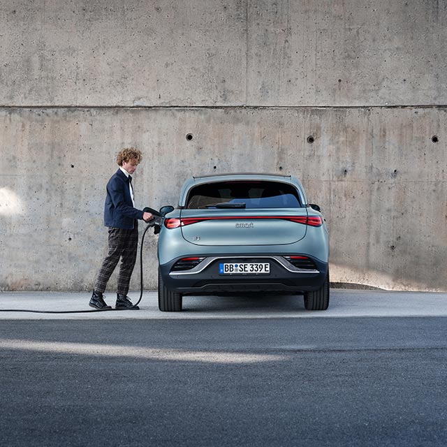 Rear view of a man charging his blue smart #3 electric car