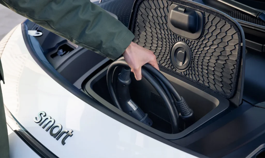 Man putting away the electric charger for his white smart #1 electric car