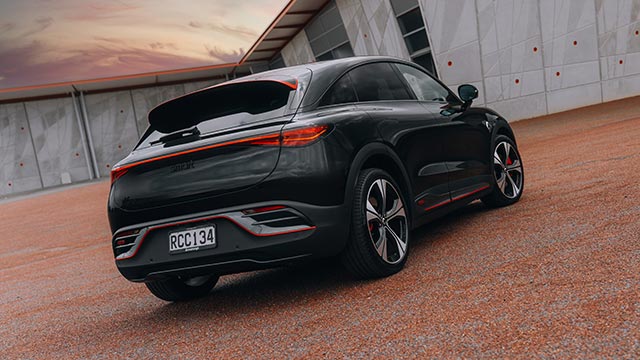 Rear three quarter view of a black smart #3 electric car parked on red pebble outside a concrete building