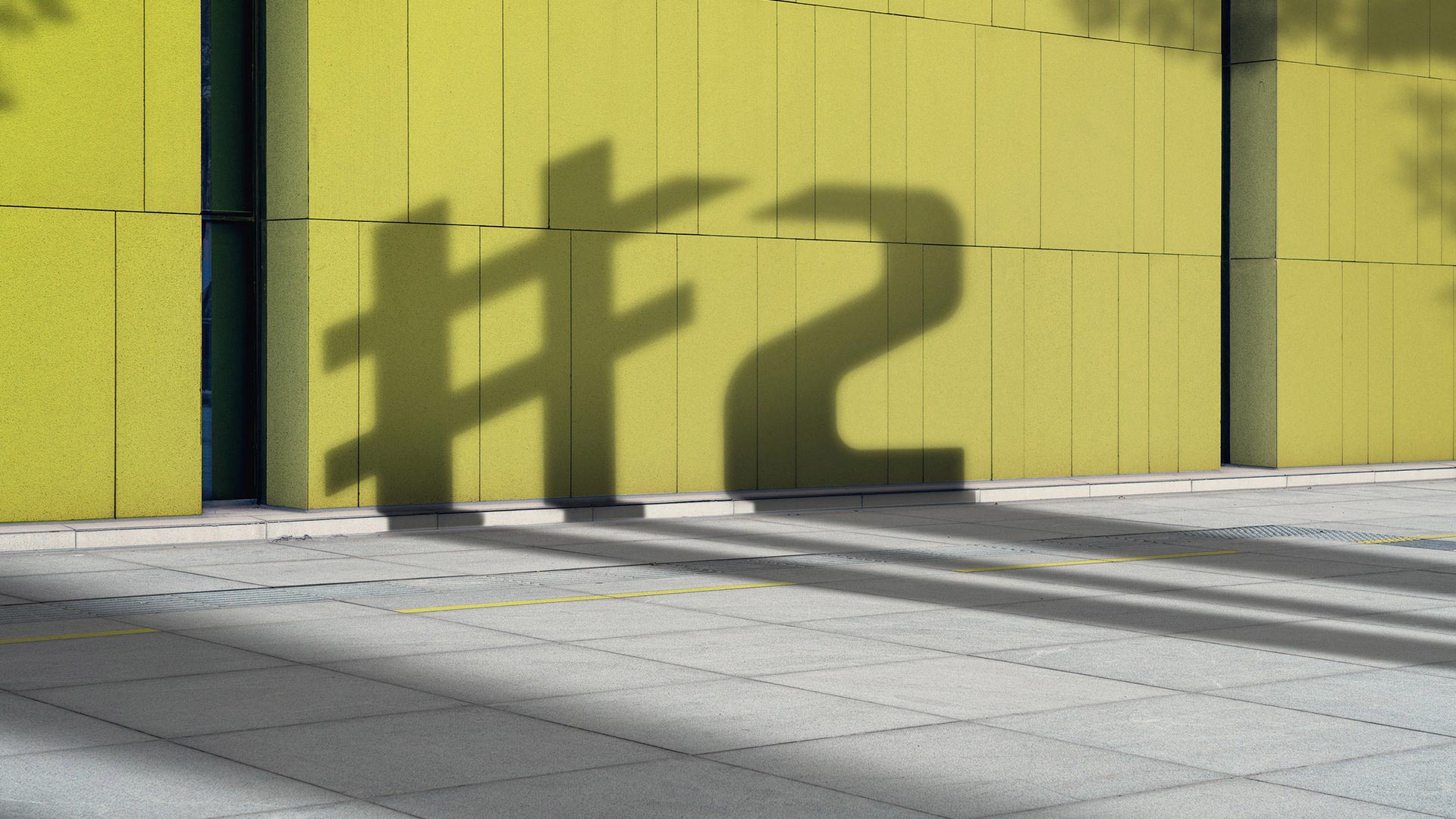 smart '#2' logo shadow seen on a yellow wall